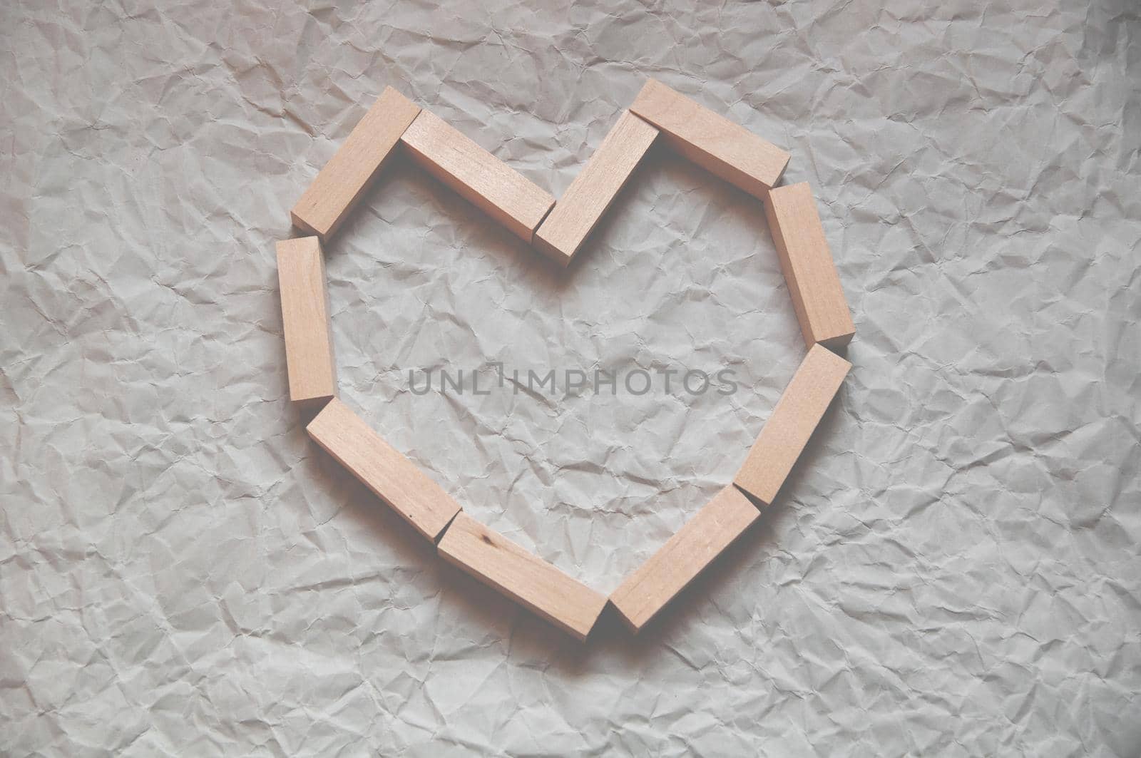 background of crumpled craft paper with wooden rectangles laid out in the shape of a heart in a minimalist style