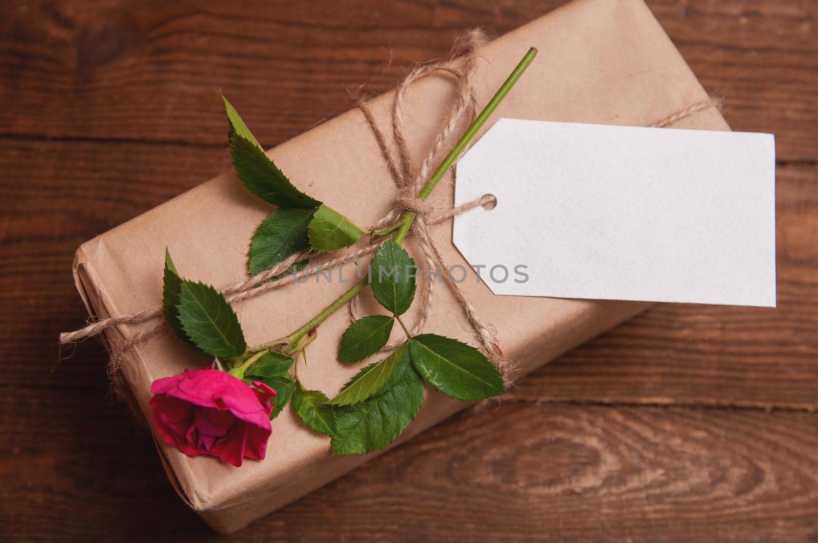 gift wrapped in craft paper on top of a flower rose tied with twine by ozornina