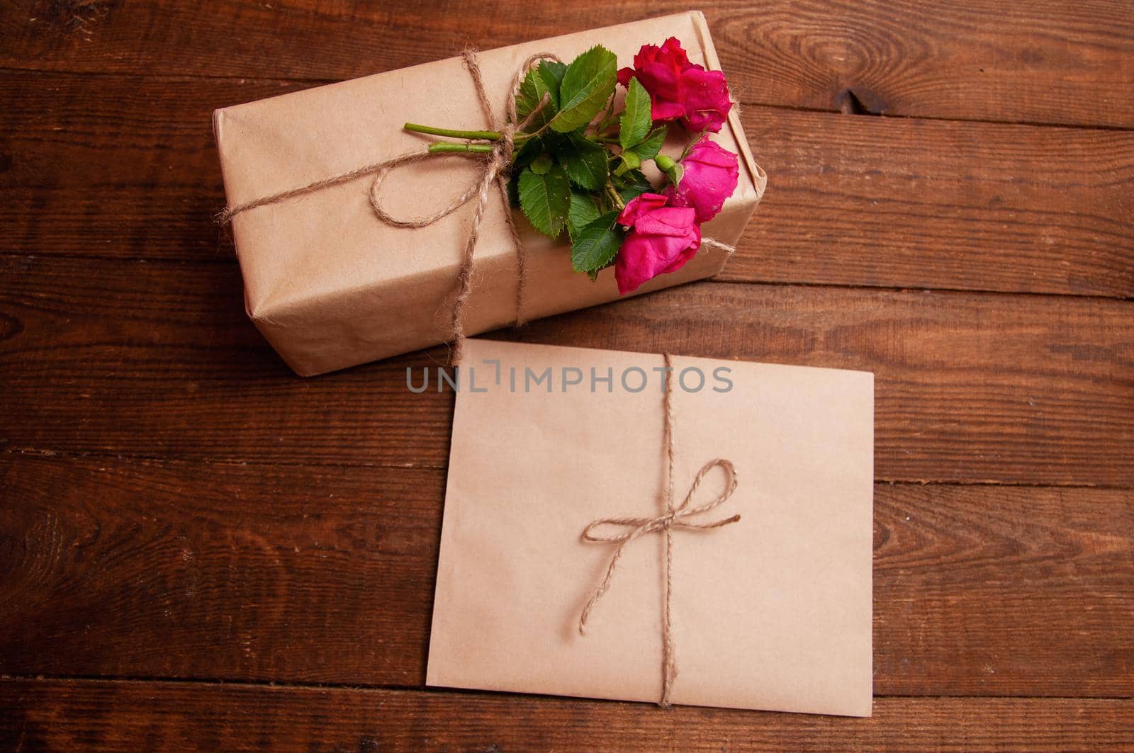 gift wrapped in craft paper on top of a flower rose tied with twine, which lies on a wooden table