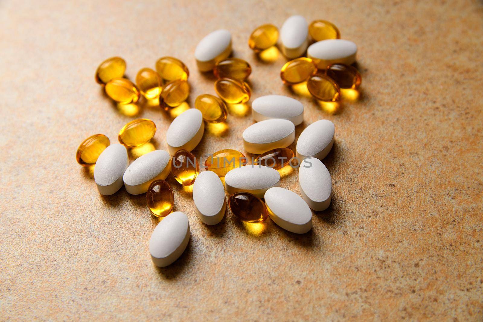 Vitamin D and fish oil capsules randomly lie on the background