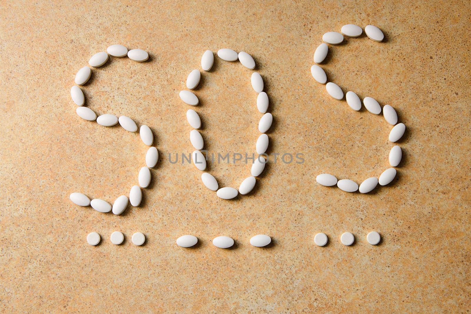 white vitamin D pills lie on the background of a concrete countertop lined with the word sos morse