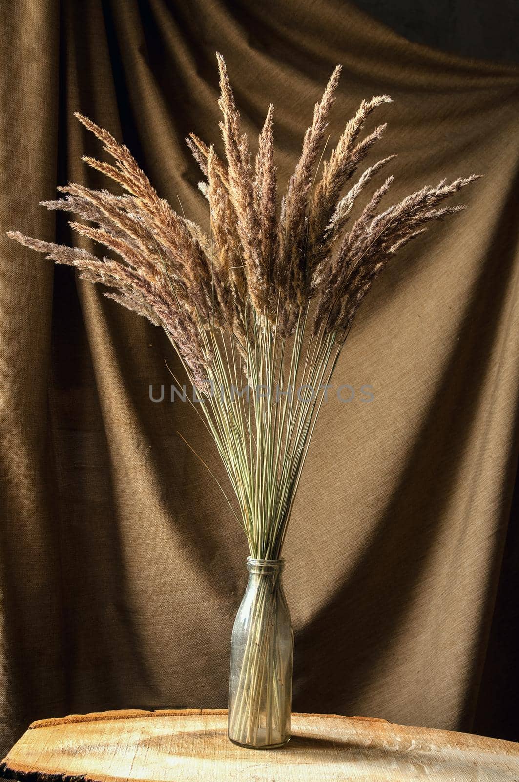 bouquet of wild flowers in glass vase on brown background