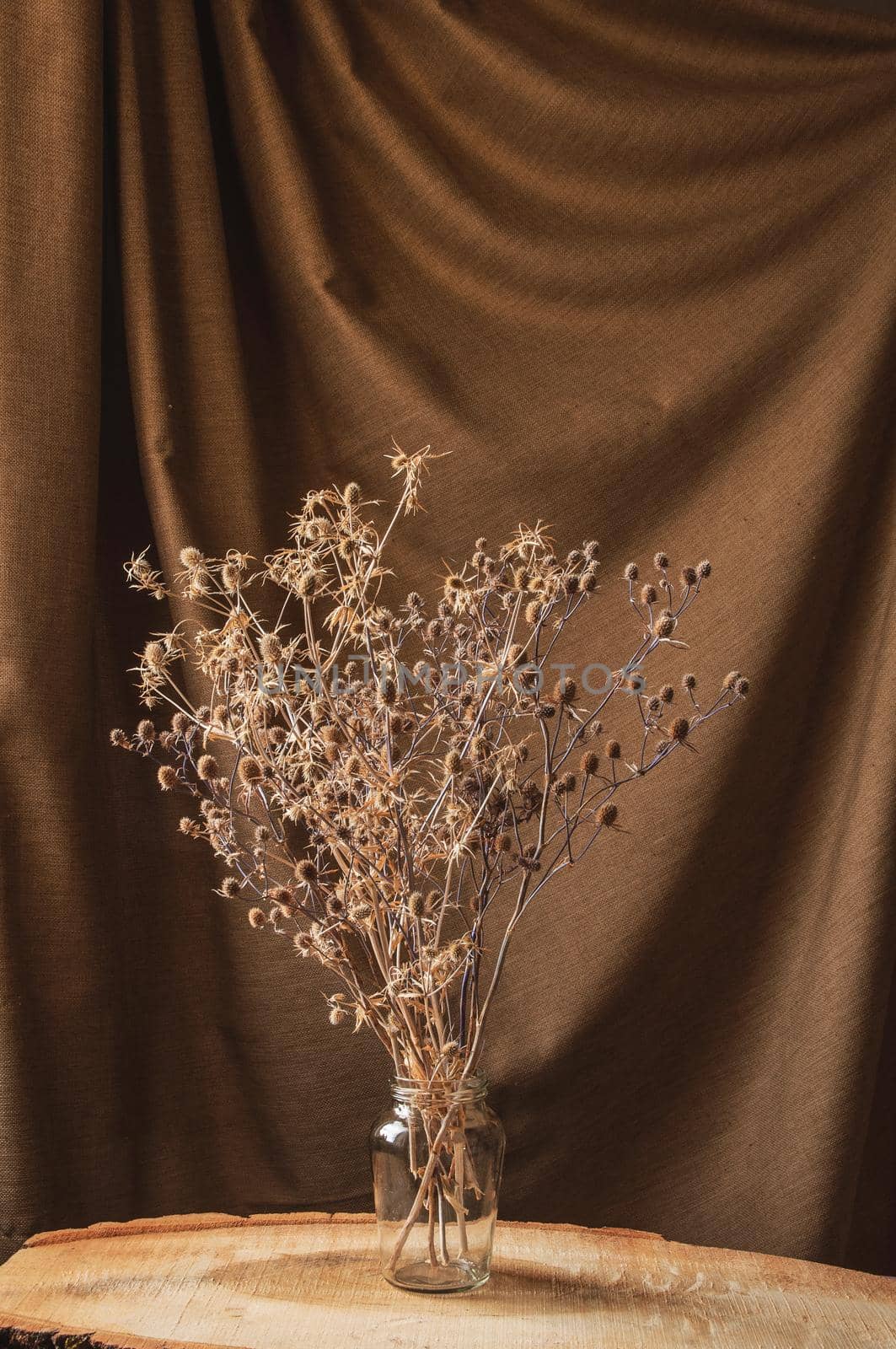 bouquet of wild flowers in glass vase on brown background