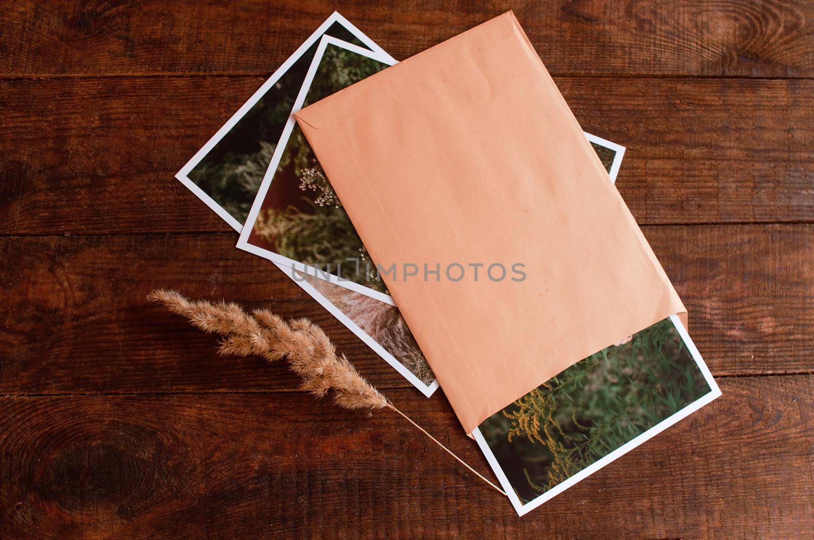 photos are enclosed in a beige envelope, located on a brown wooden table