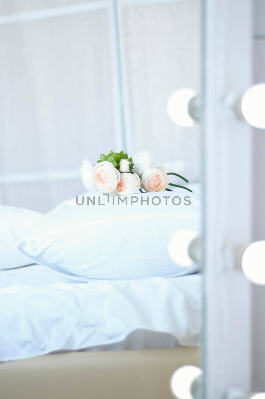 bouquet of flowers on the bed and a mirror with light bulbs