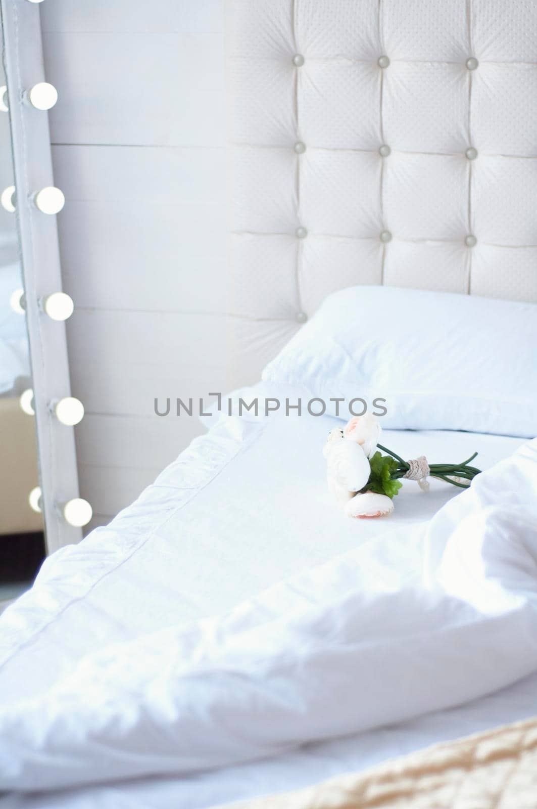 bouquet of flowers on the bed and a mirror with light bulbs