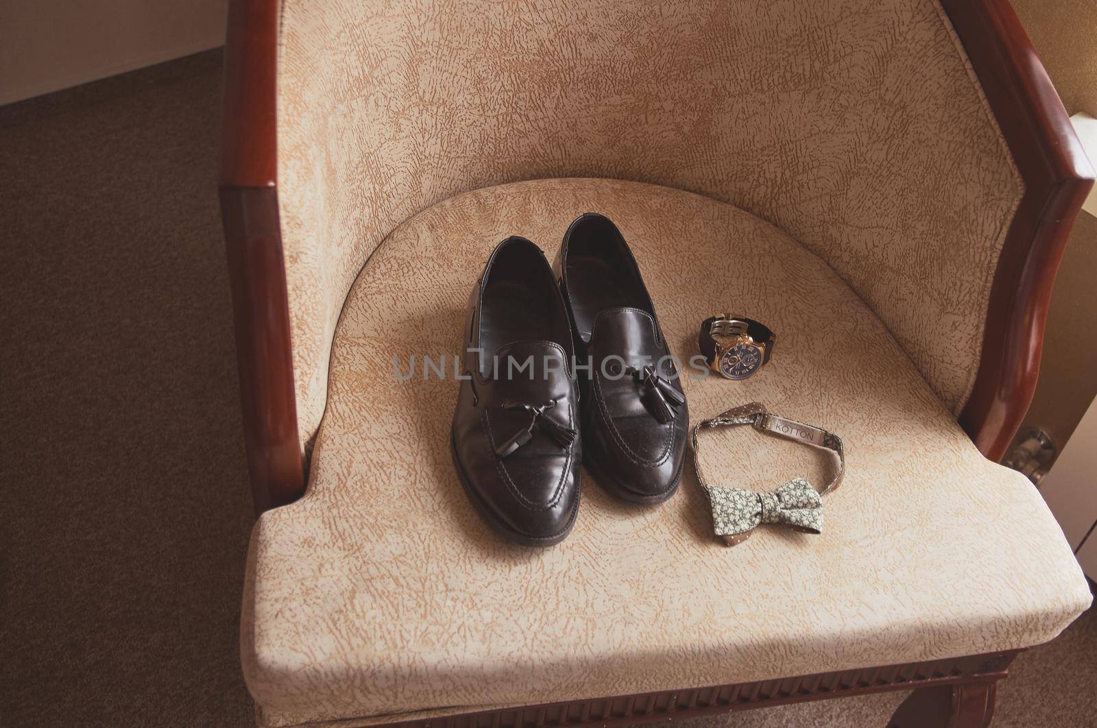 wedding mens shoes on an armchair with clock and bow tie