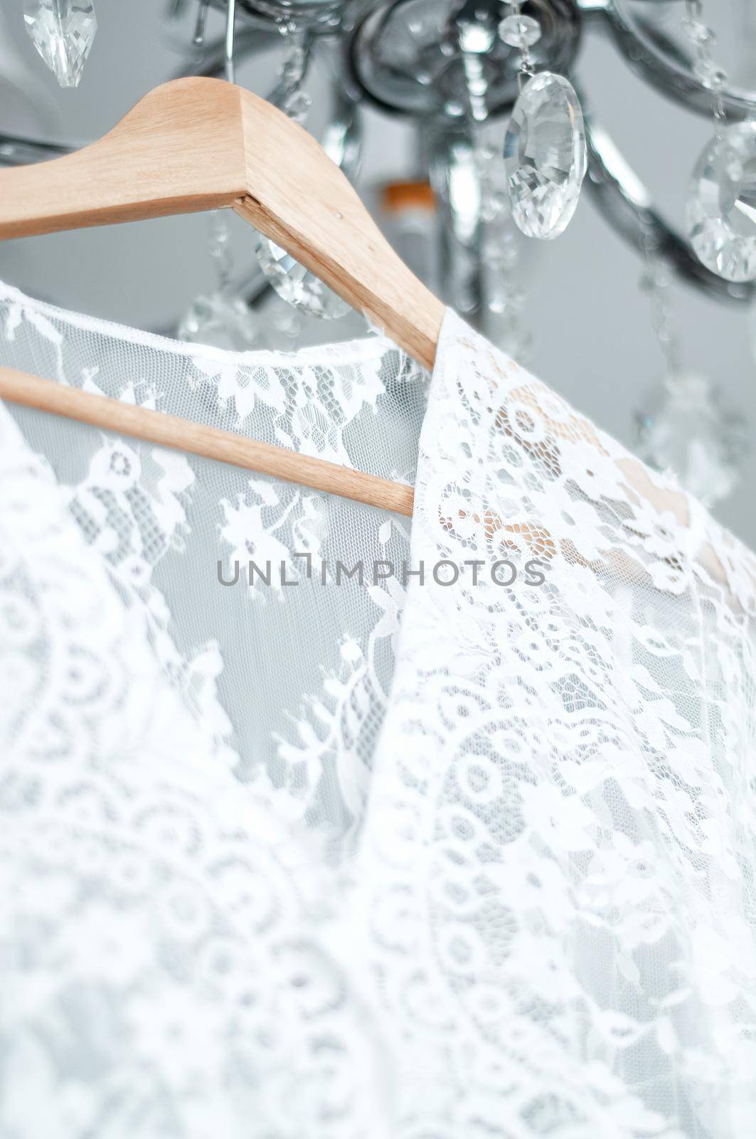 wedding peignoir on a hanger hanging on a chandelier opposite the window