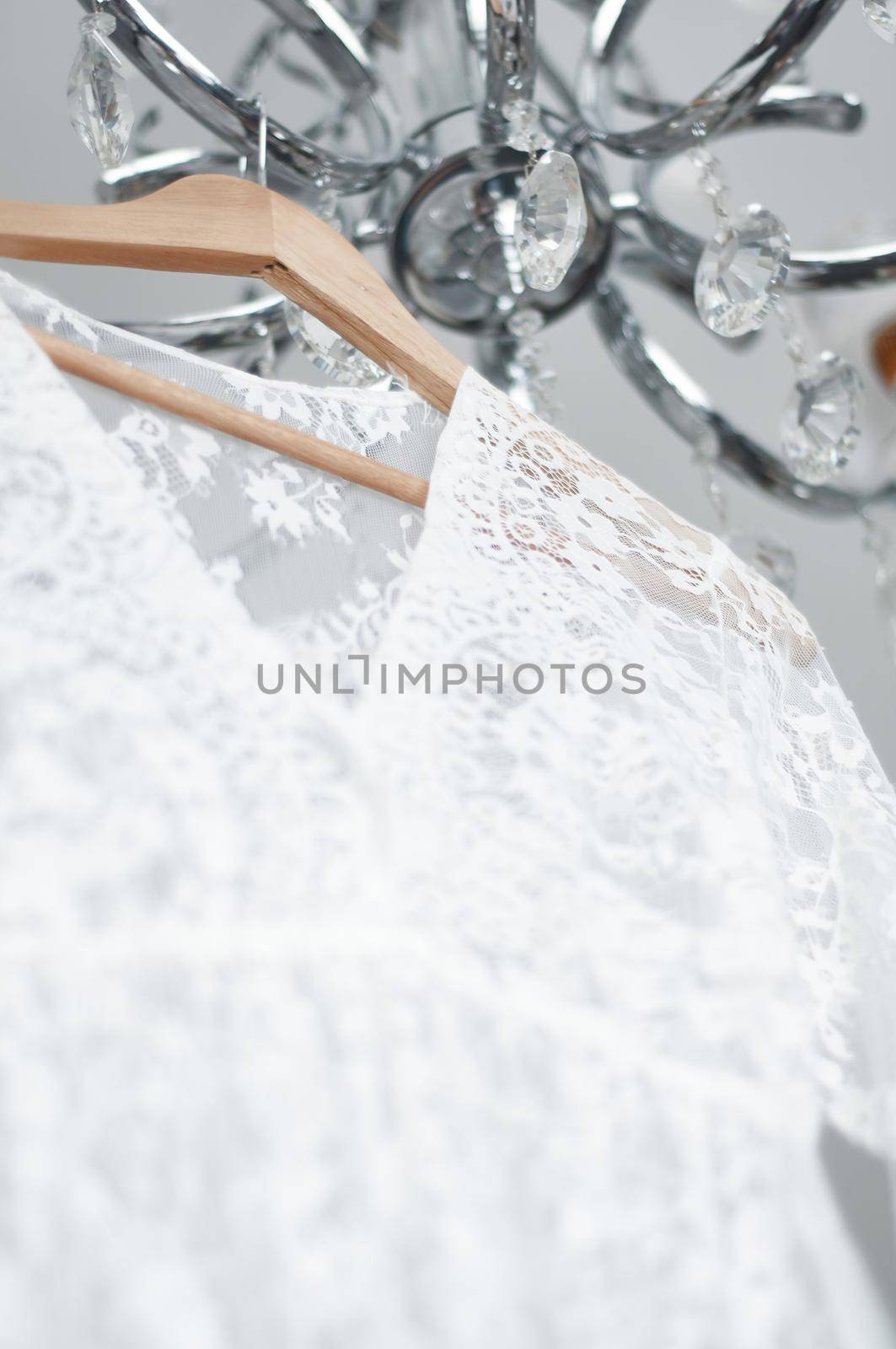 wedding peignoir on a hanger hanging on a chandelier by ozornina