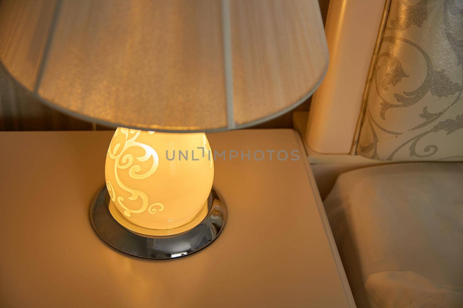 table lamp on a bedside table in a bedroom with gray walls near the bed by ozornina