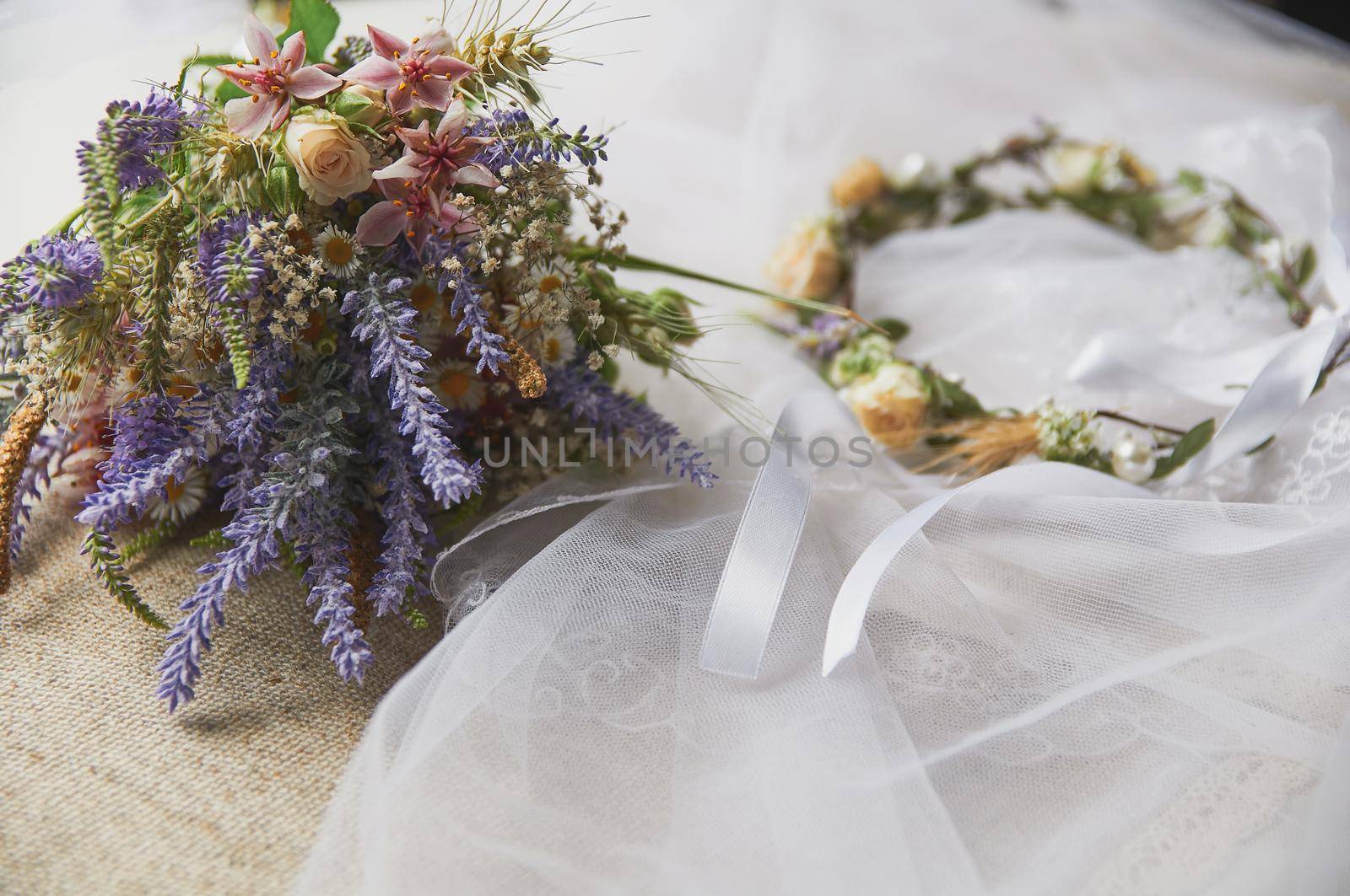 delicate wedding wreath in boho style on the table covered with a wedding veil