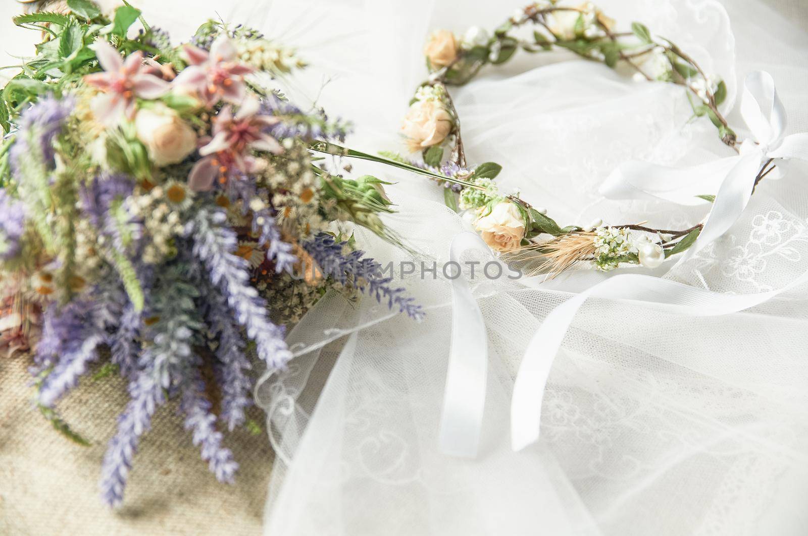 delicate wedding wreath in boho style on the table covered with a wedding veil