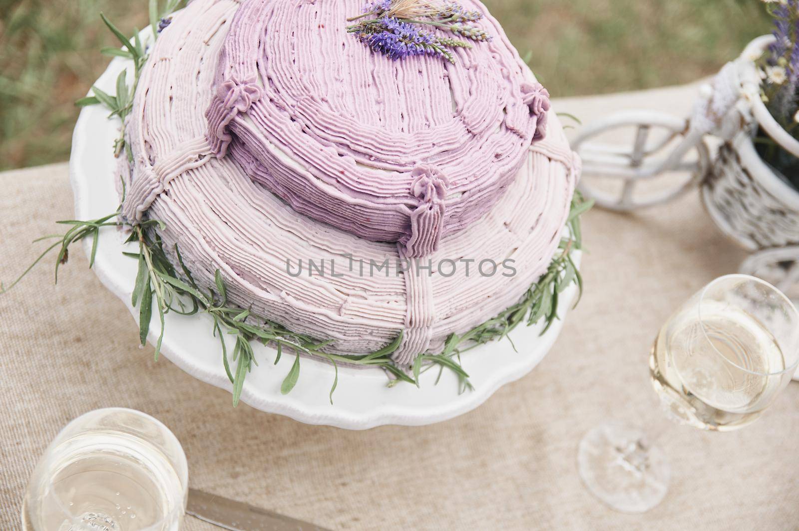 boho style wedding cake on a table covered with a linen tablecloth, with plates, glasses, knife fork and a bouquet of flowers