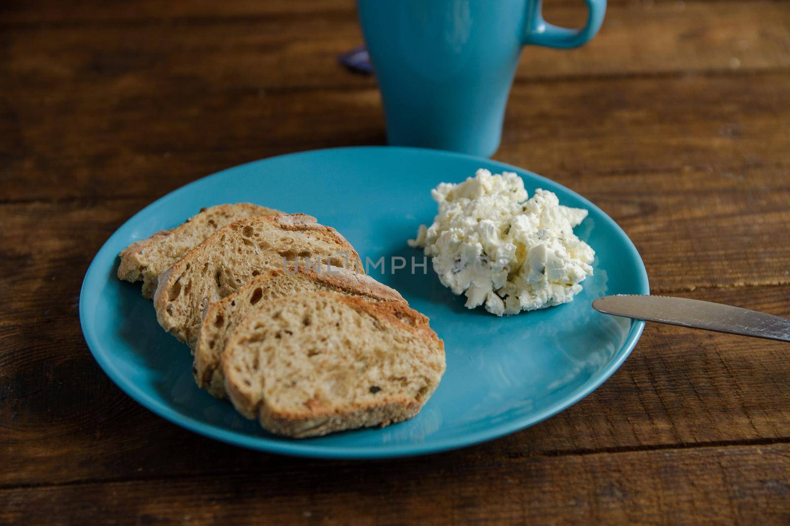 Breakfast bread toast on a blue plate with soft cheese by ozornina