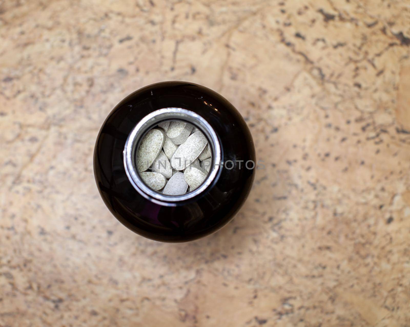 Various capsules and tablets with food additives or medicines in a jar. The view from the top