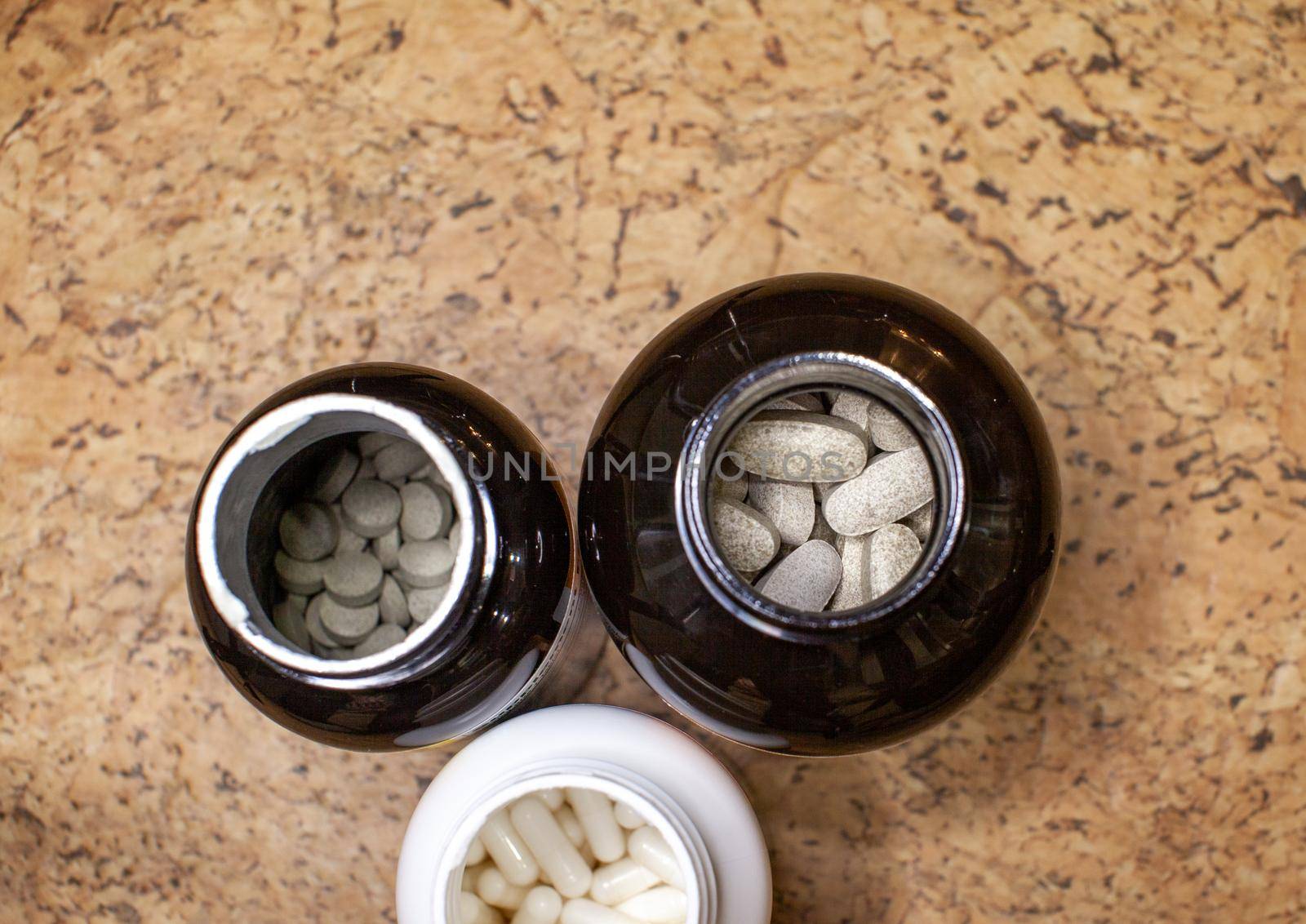 Various capsules and tablets with food additives or medicines in a jar. The view from the top