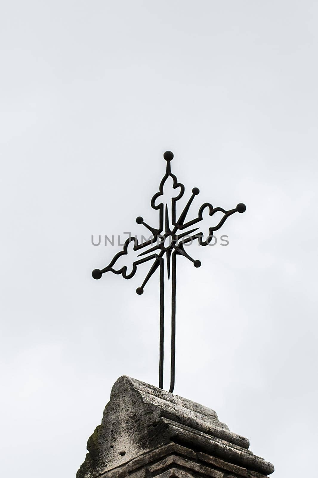 iron crucifix placed above a church on a gray day
