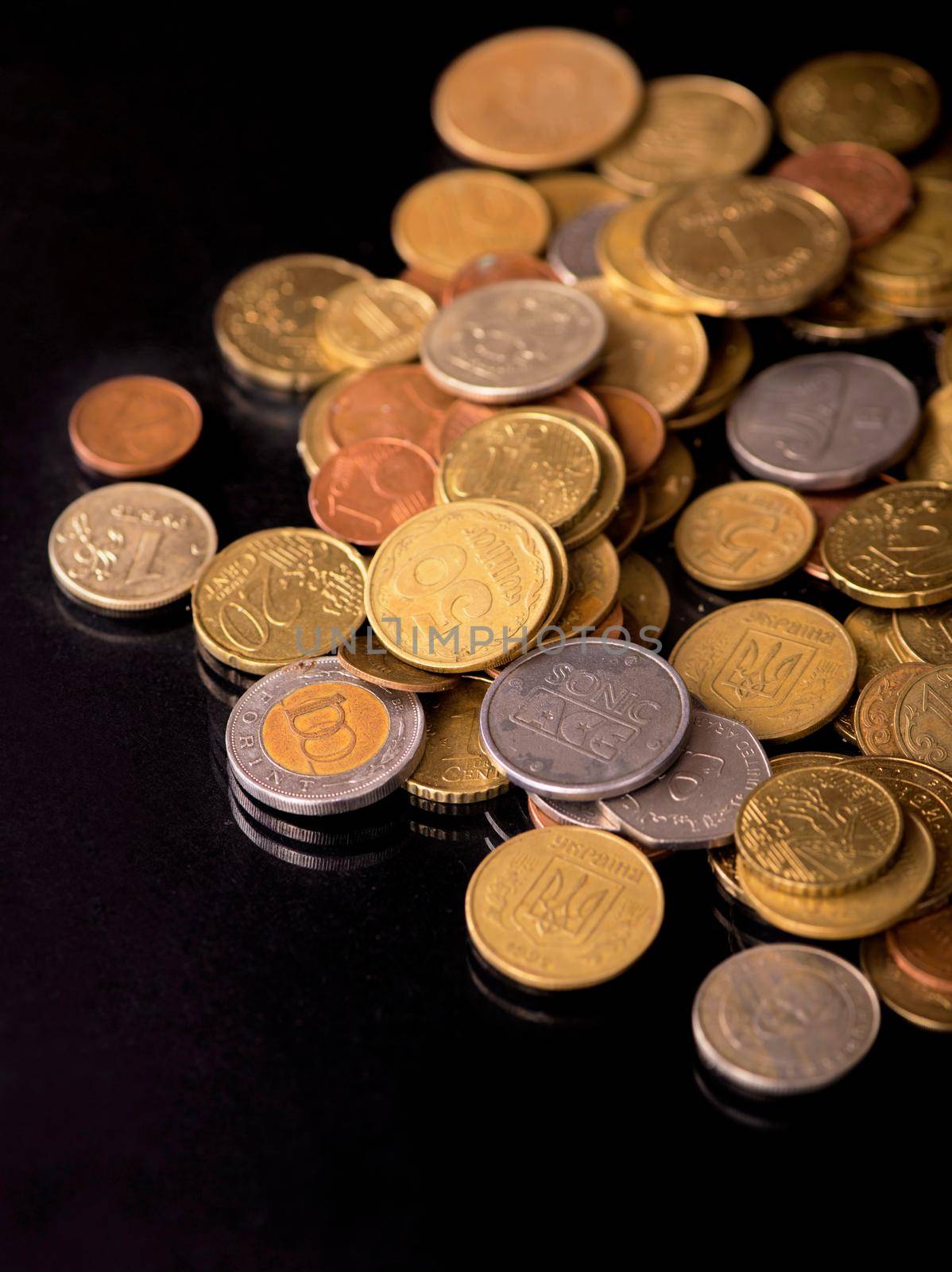 Stacks cf different country coins on black background.