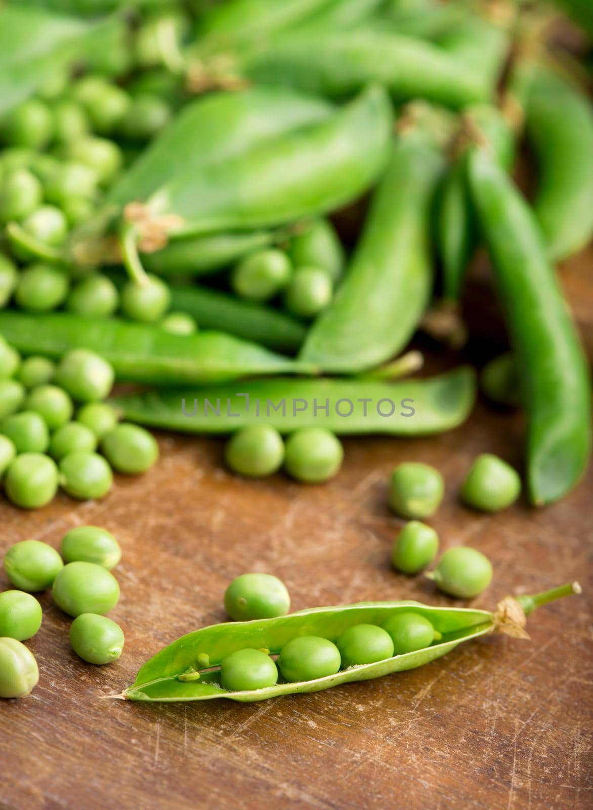 RAW baby peas in small white bowl, over retro wooden boards. Close-up. by aprilphoto