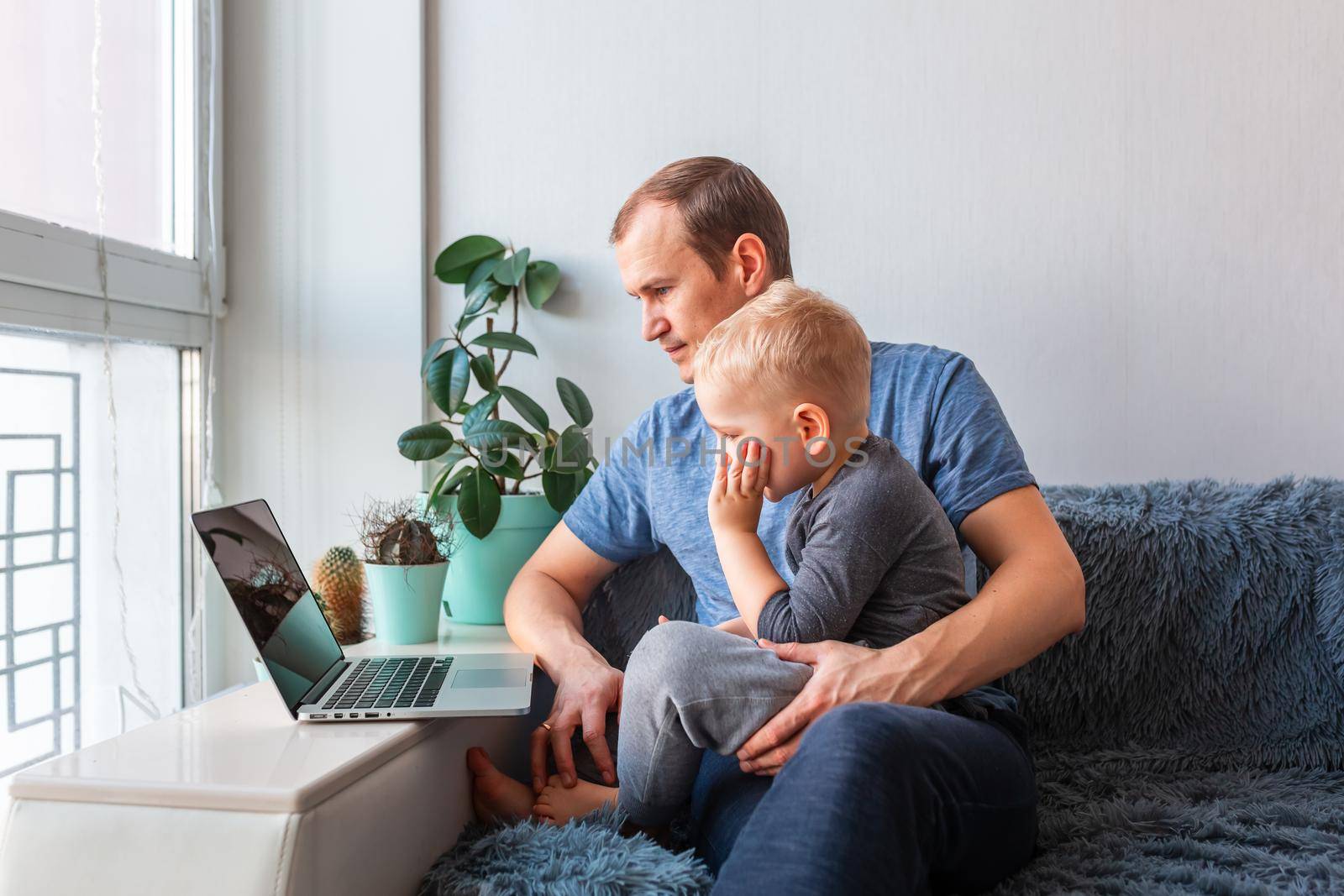 Father and son having video call with grandparents on laptop during covid quarantine lockdown. by Len44ik