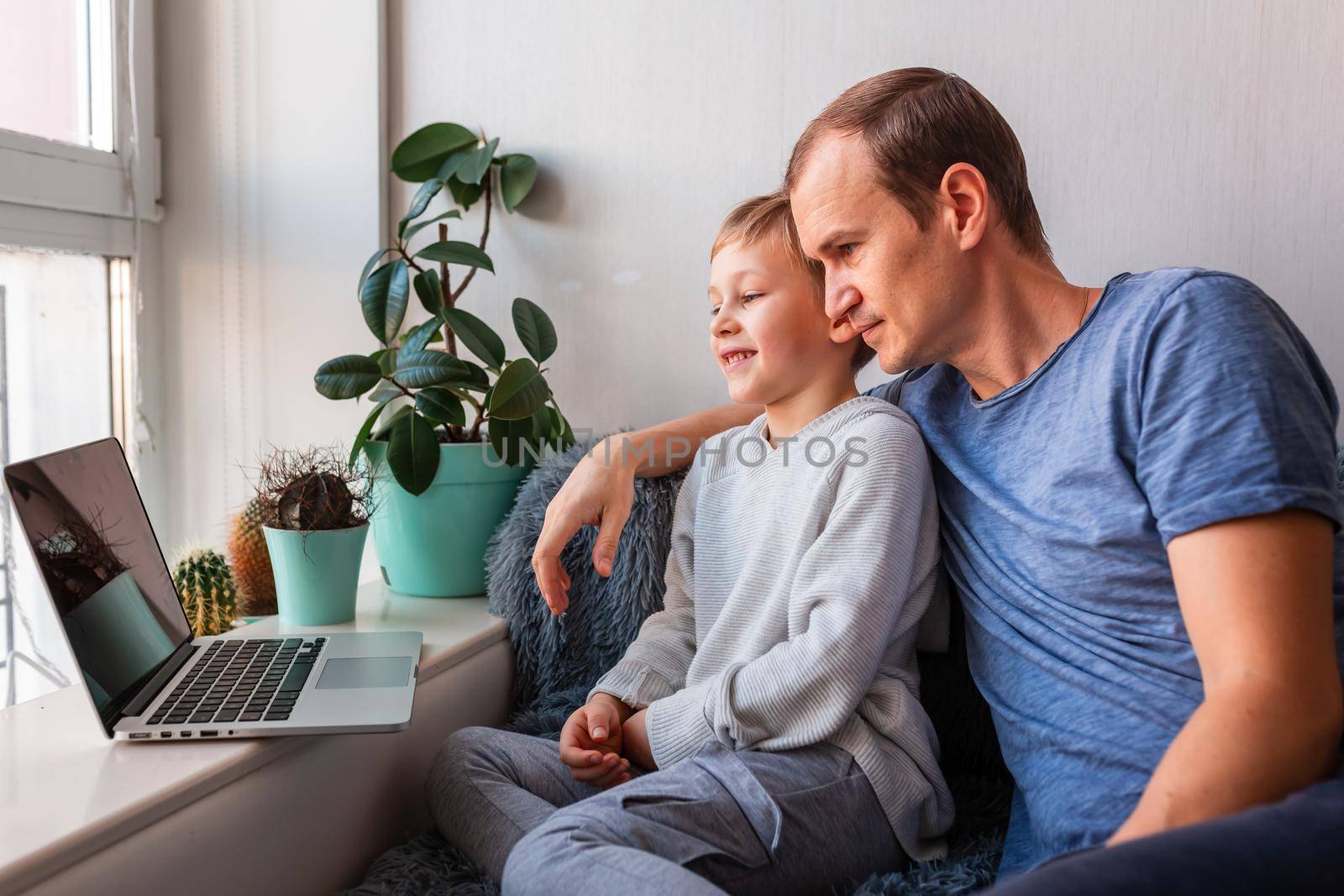 Father and son having video call with grandparents on laptop during covid quarantine lockdown. by Len44ik