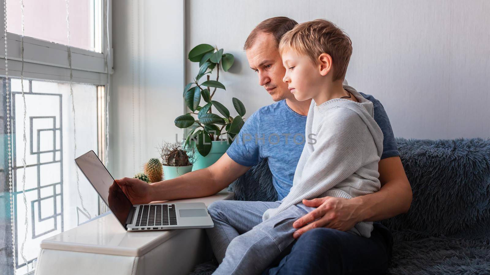 Father and son having video call with grandparents on laptop during covid quarantine lockdown. by Len44ik