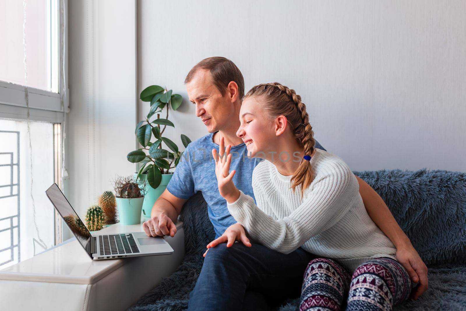 Father and daughter having video call with grandparents on laptop during covid quarantine lockdown. by Len44ik