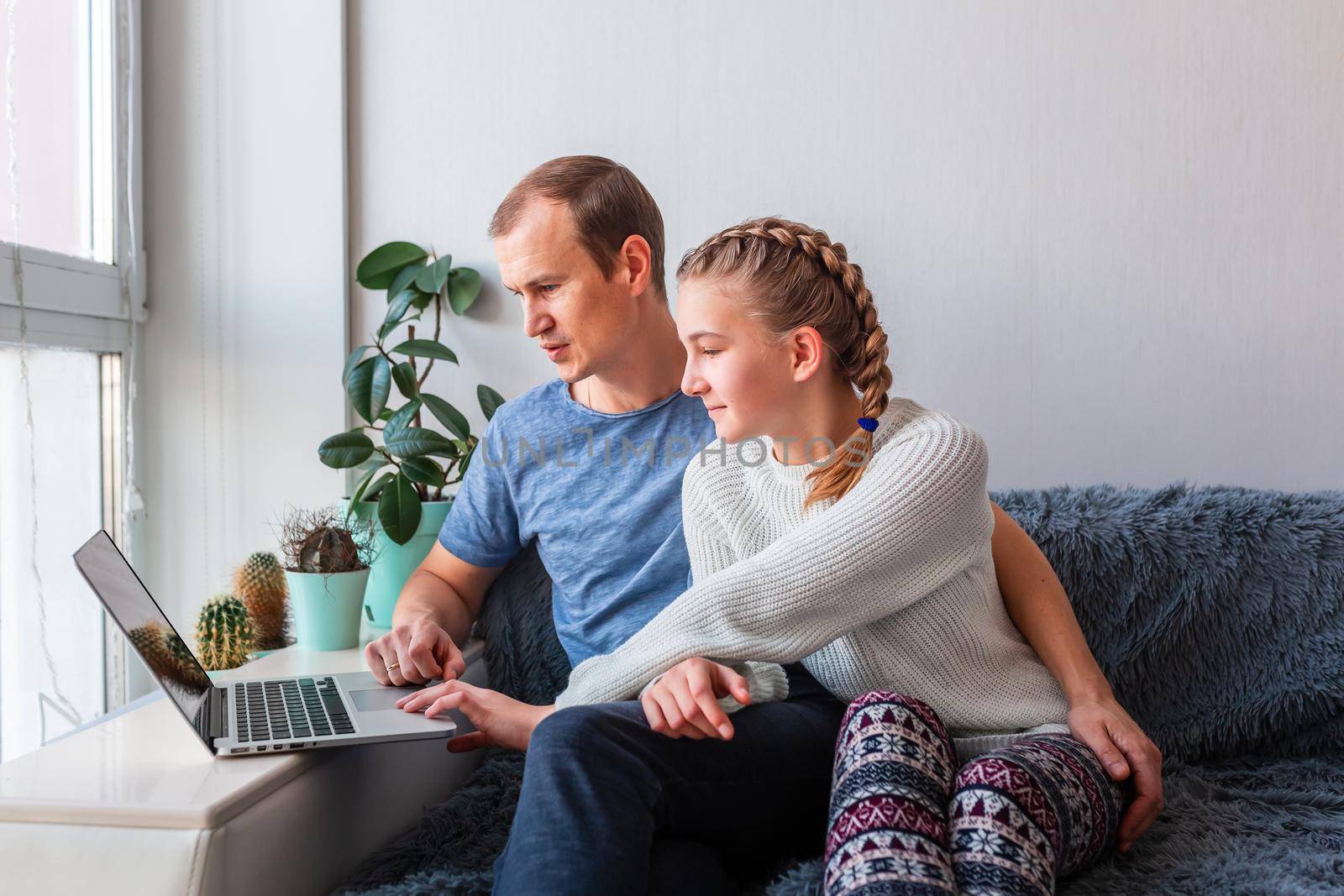 Father and daughter having video call with grandparents on laptop during covid quarantine lockdown. by Len44ik