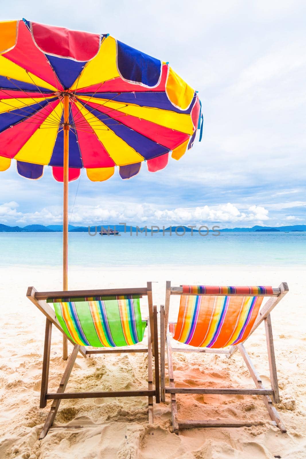 Two colorful beach chair with umbrella. by Gamjai