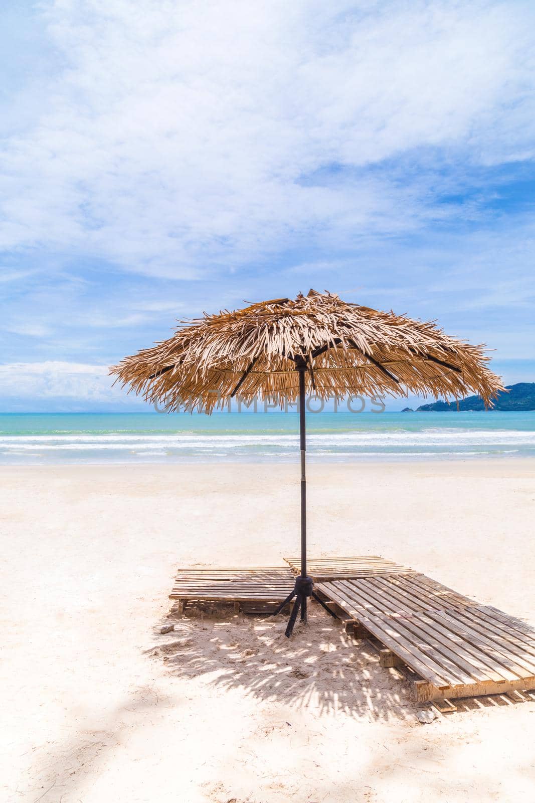 Beach Umbrella made of palm leafs on a perfect white beach in front of Sea in Phuket Isaland, Thailand.