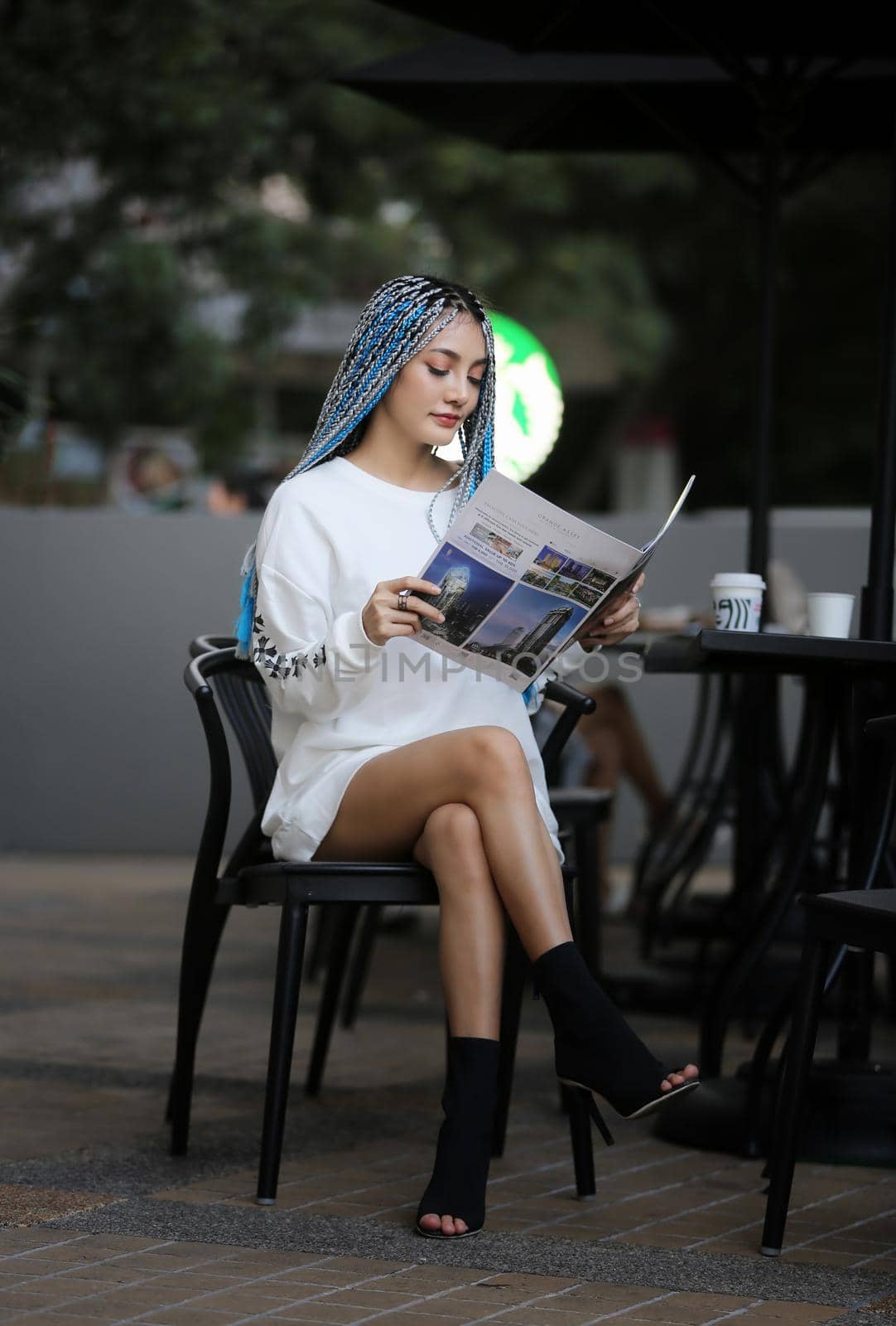 Happy stylish young hipster woman with long blue hair pink jacket, hat on the street in urban city.