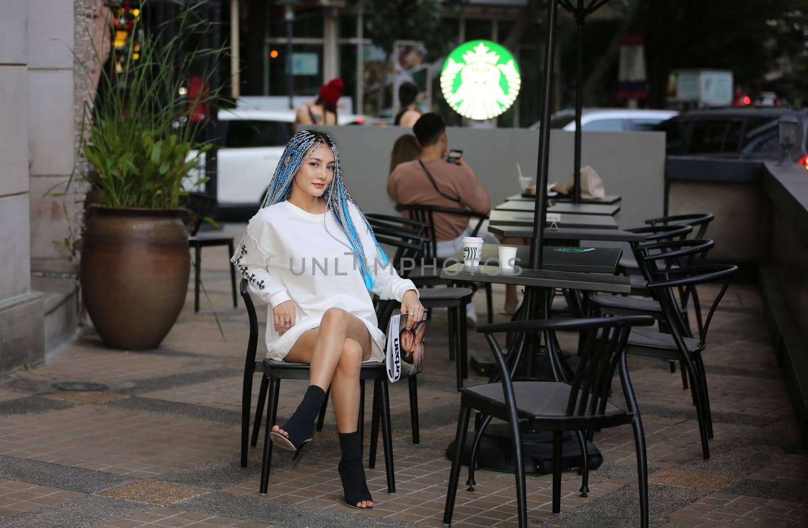 Happy stylish young hipster woman with long blue hair pink jacket, hat on the street in urban city. by chuanchai