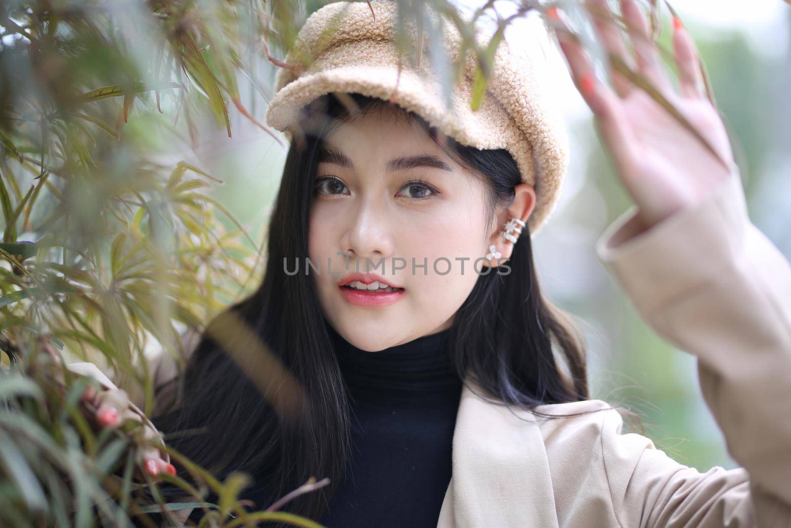 Portrait of young beautiful woman in winter clothes. while posing on snow background. Outdoor close-up photo of female model with romantic smile chilling in park in winter. by chuanchai