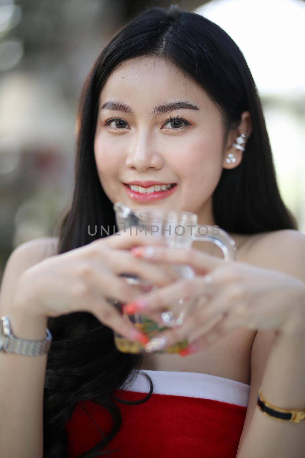 Beautiful young woman smiling while holding a glass of water at home. Lifestyle concept by chuanchai