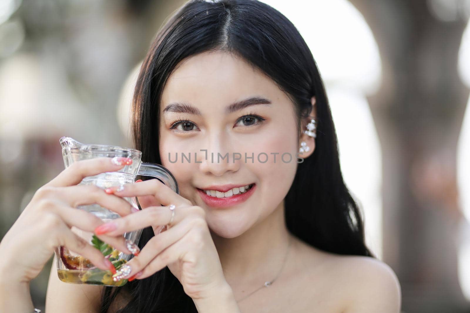 Beautiful young woman smiling while holding a glass of water at home. Lifestyle concept