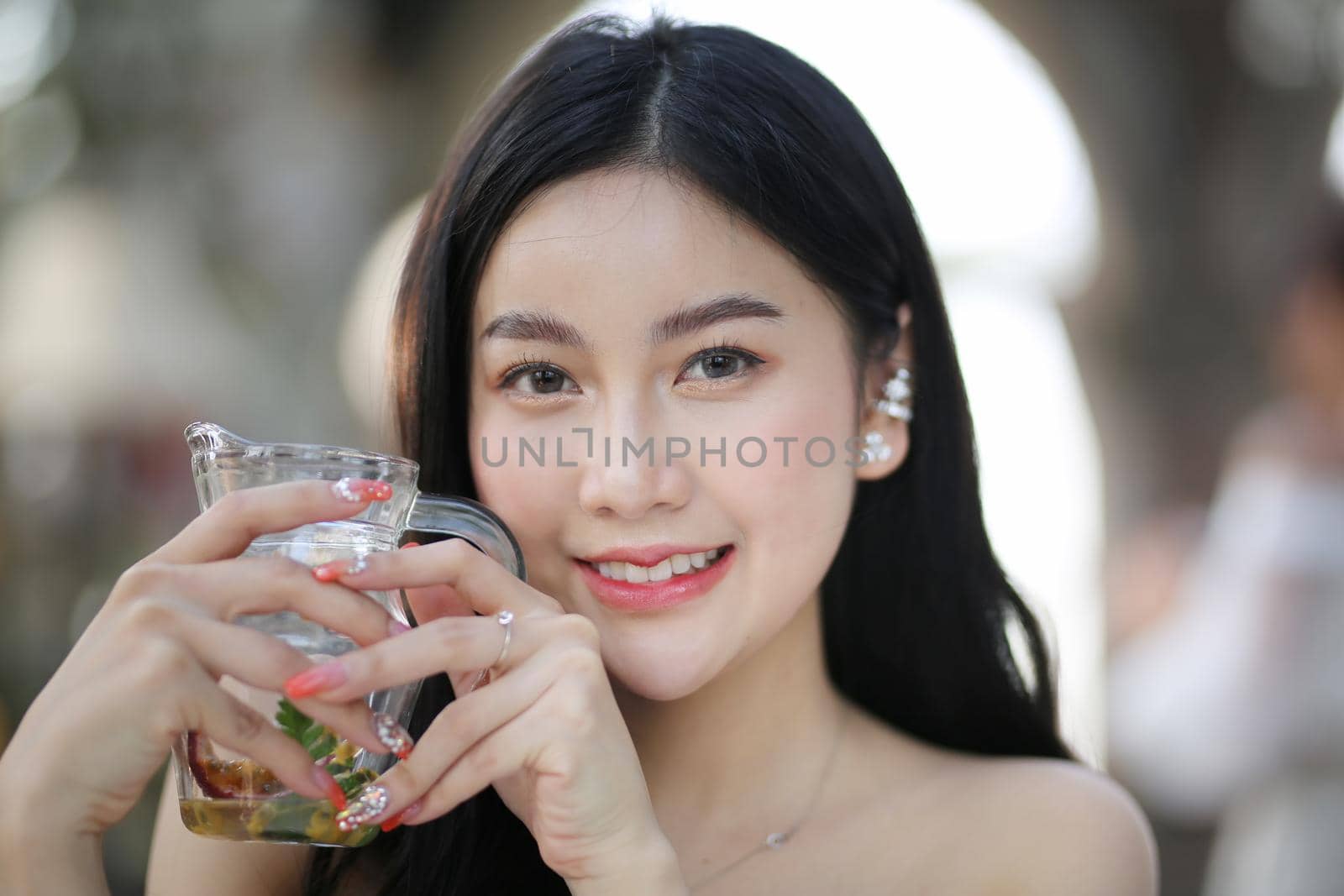 Beautiful young woman smiling while holding a glass of water at home. Lifestyle concept by chuanchai