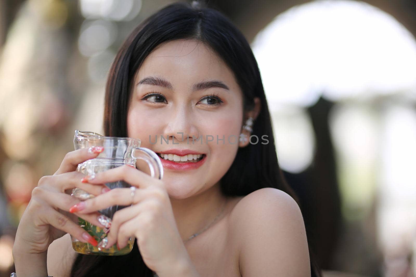 Beautiful young woman smiling while holding a glass of water at home. Lifestyle concept by chuanchai