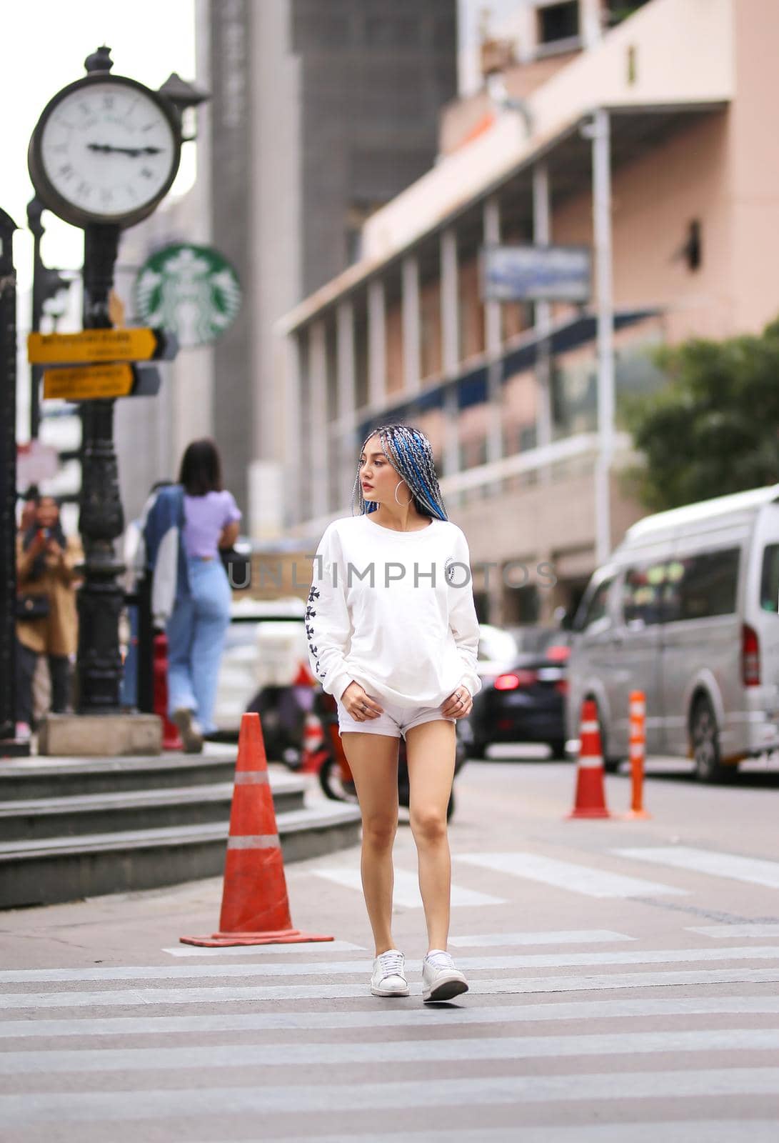 Happy stylish young hipster woman with long blue hair pink jacket, hat on the street in urban city.