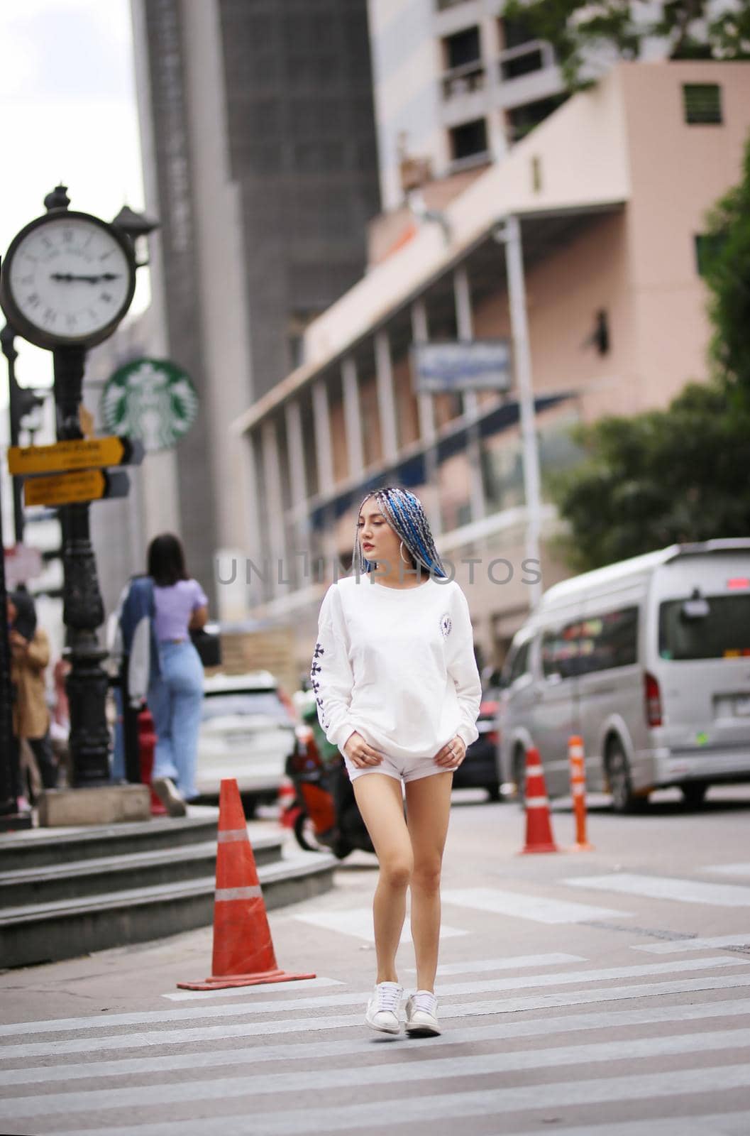 Happy stylish young hipster woman with long blue hair pink jacket, hat on the street in urban city.