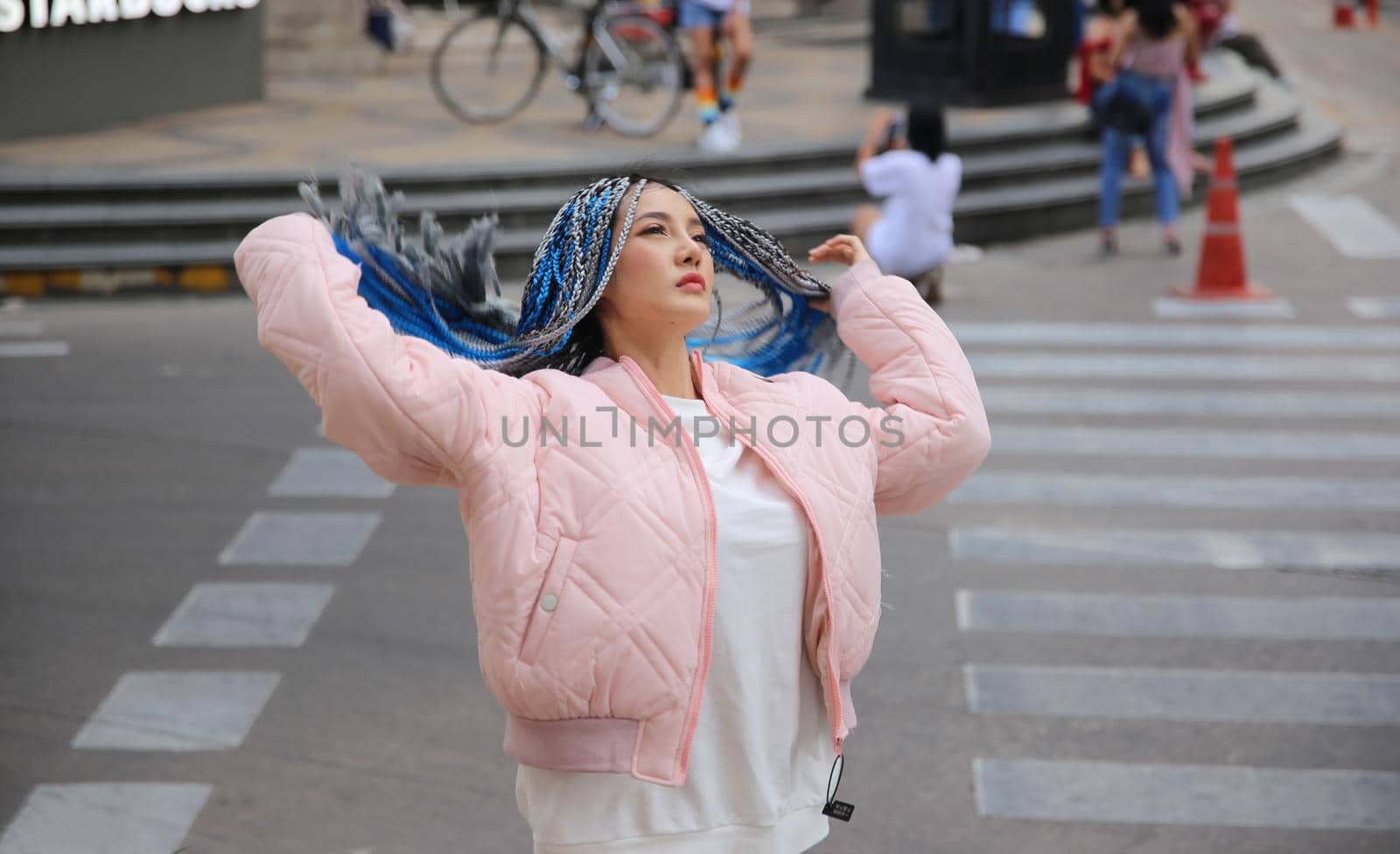 Happy stylish young hipster woman with long blue hair pink jacket, hat on the street in urban city. by chuanchai