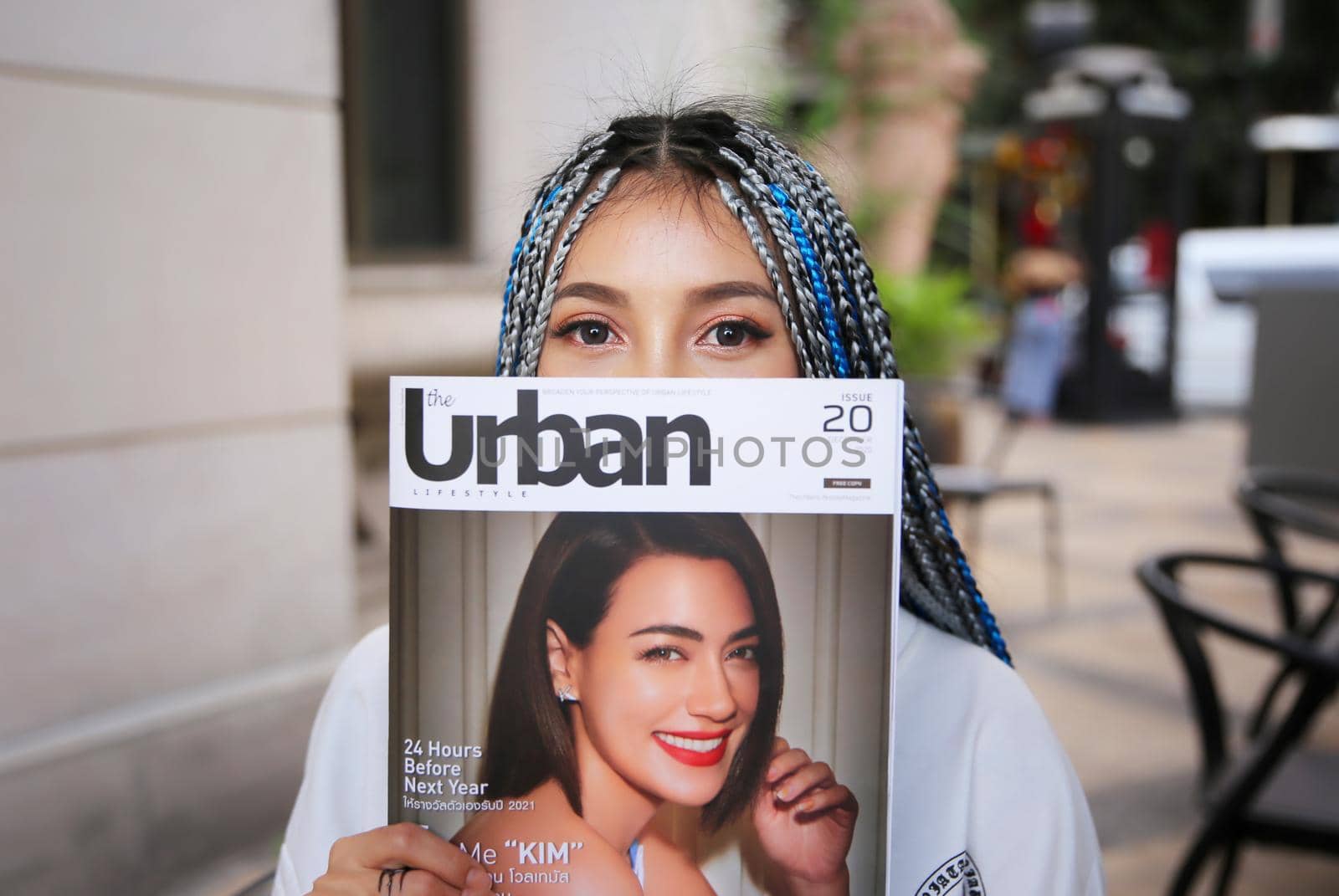 Happy stylish young hipster woman with long blue hair pink jacket, hat on the street in urban city. by chuanchai