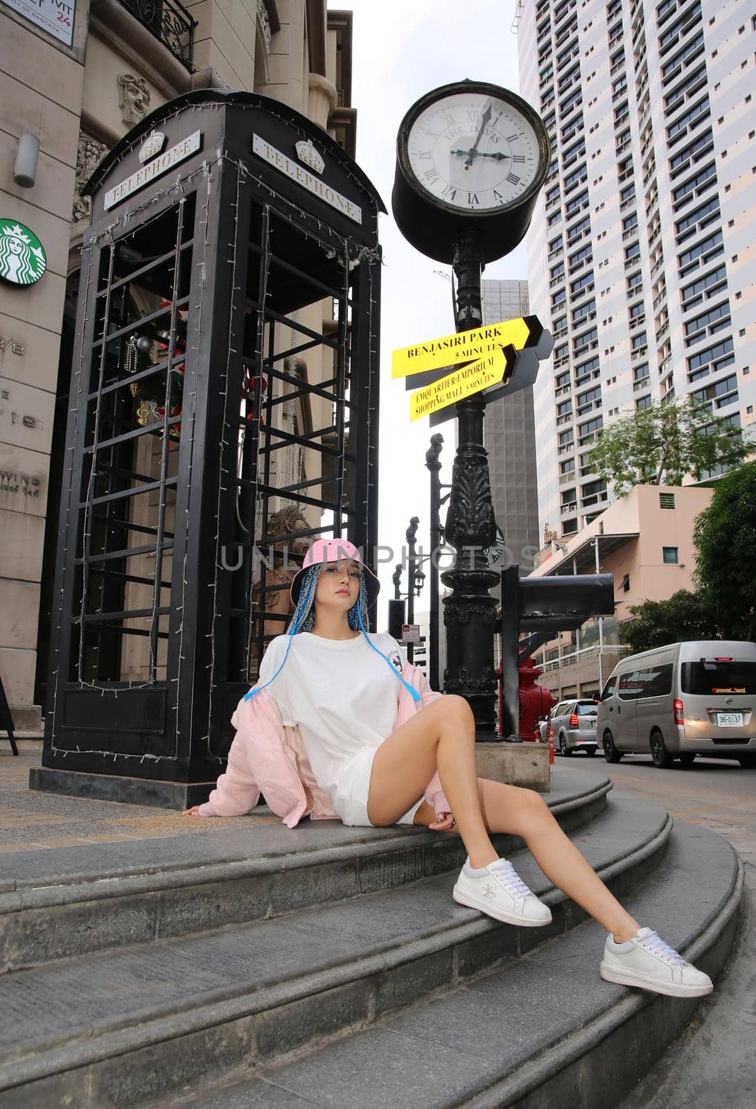 Happy stylish young hipster woman with long blue hair pink jacket, hat on the street in urban city. by chuanchai