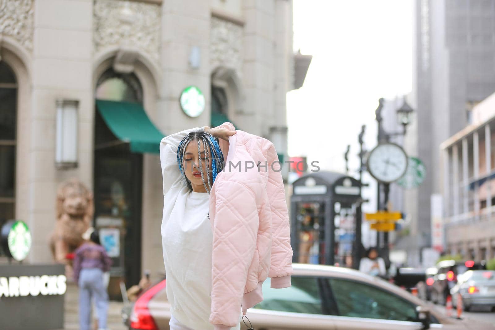 Happy stylish young hipster woman with long blue hair pink jacket, hat on the street in urban city. by chuanchai