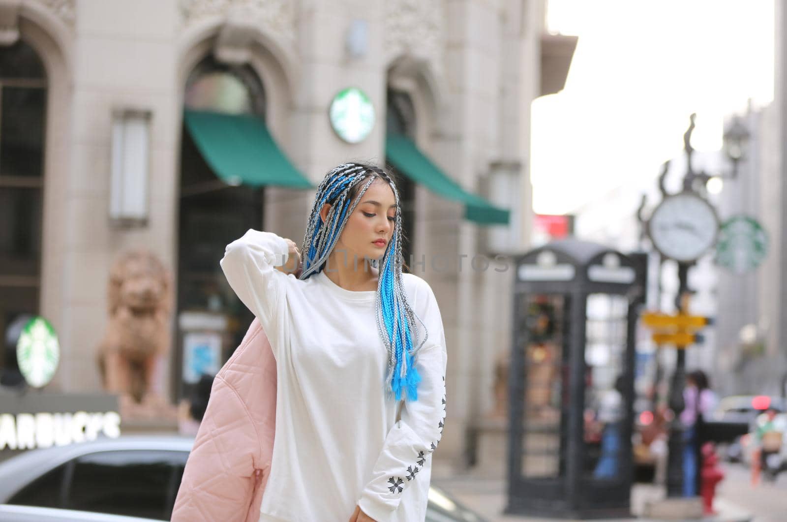 Happy stylish young hipster woman with long blue hair pink jacket, hat on the street in urban city. by chuanchai