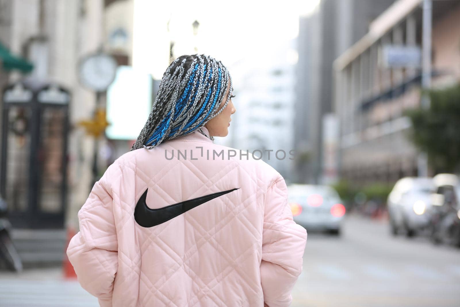 Happy stylish young hipster woman with long blue hair pink jacket, hat on the street in urban city. by chuanchai