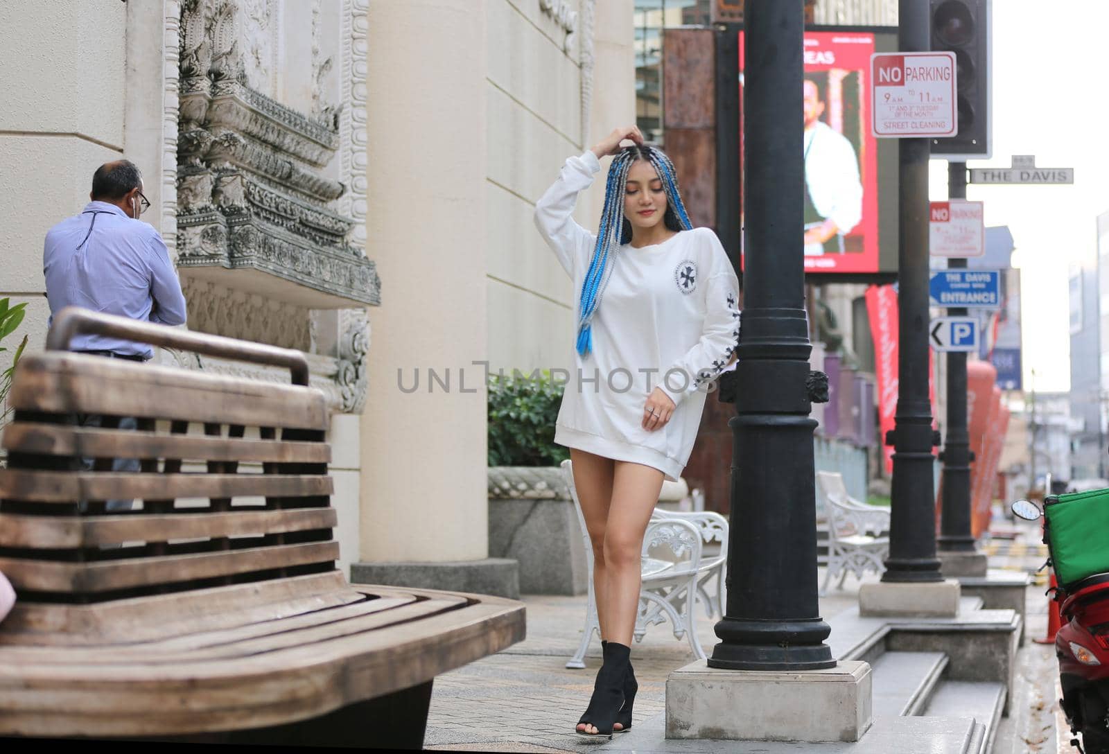 Happy stylish young hipster woman with long blue hair pink jacket, hat on the street in urban city. by chuanchai