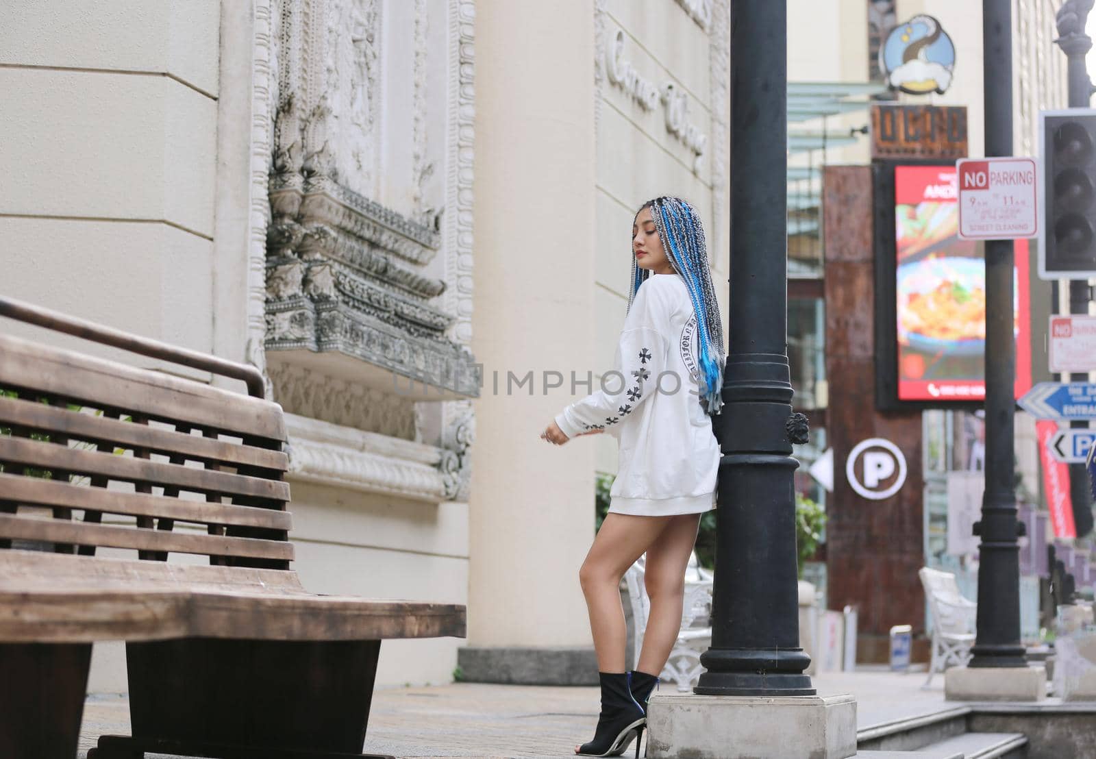 Happy stylish young hipster woman with long blue hair pink jacket, hat on the street in urban city. by chuanchai