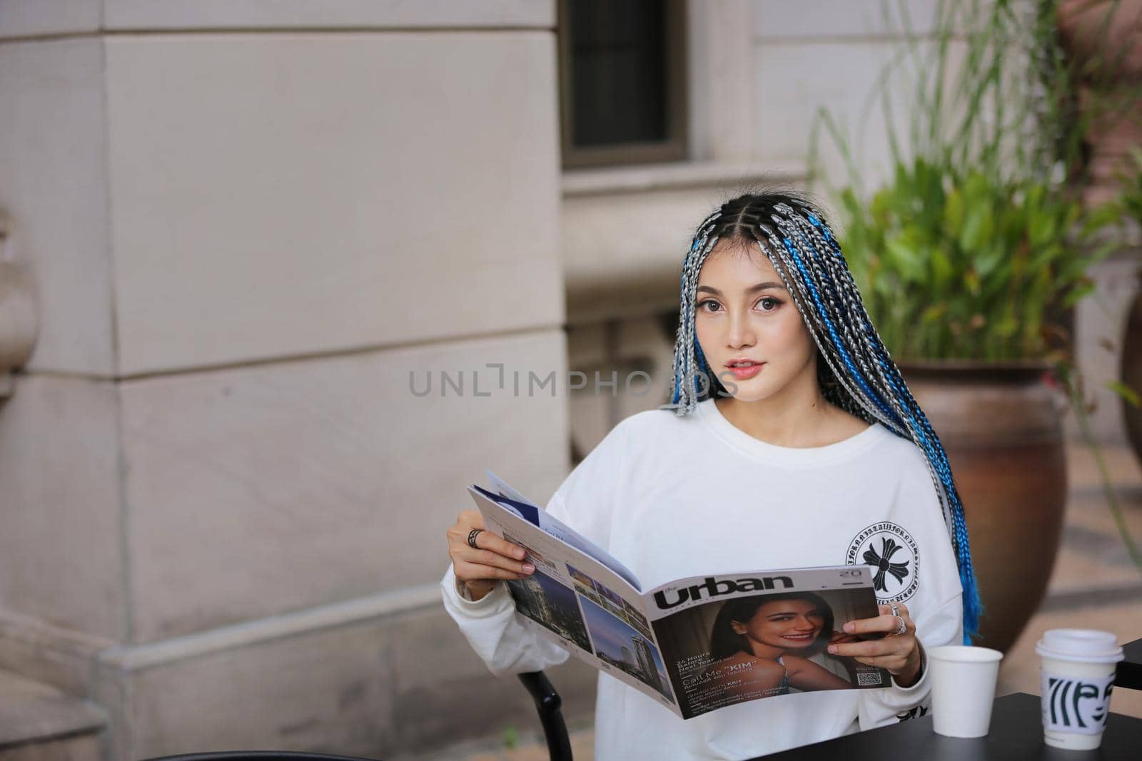 Happy stylish young hipster woman with long blue hair pink jacket, hat on the street in urban city. by chuanchai