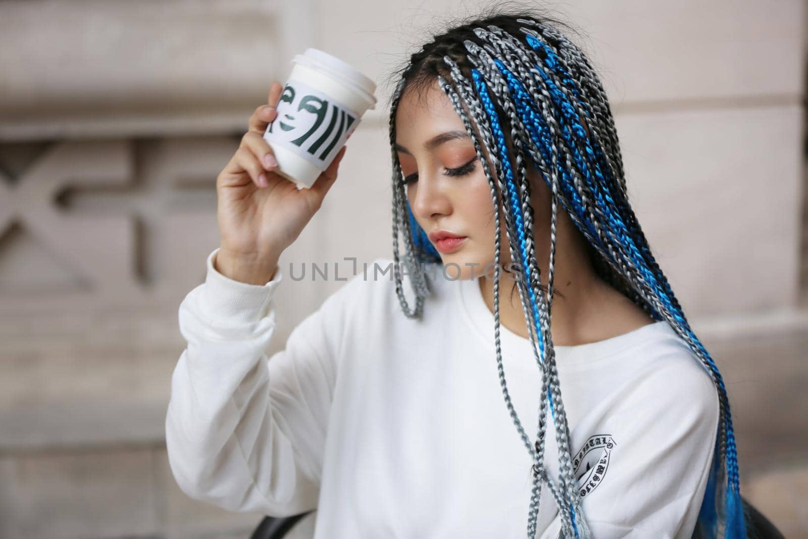 Happy stylish young hipster woman with long blue hair pink jacket, hat on the street in urban city. by chuanchai