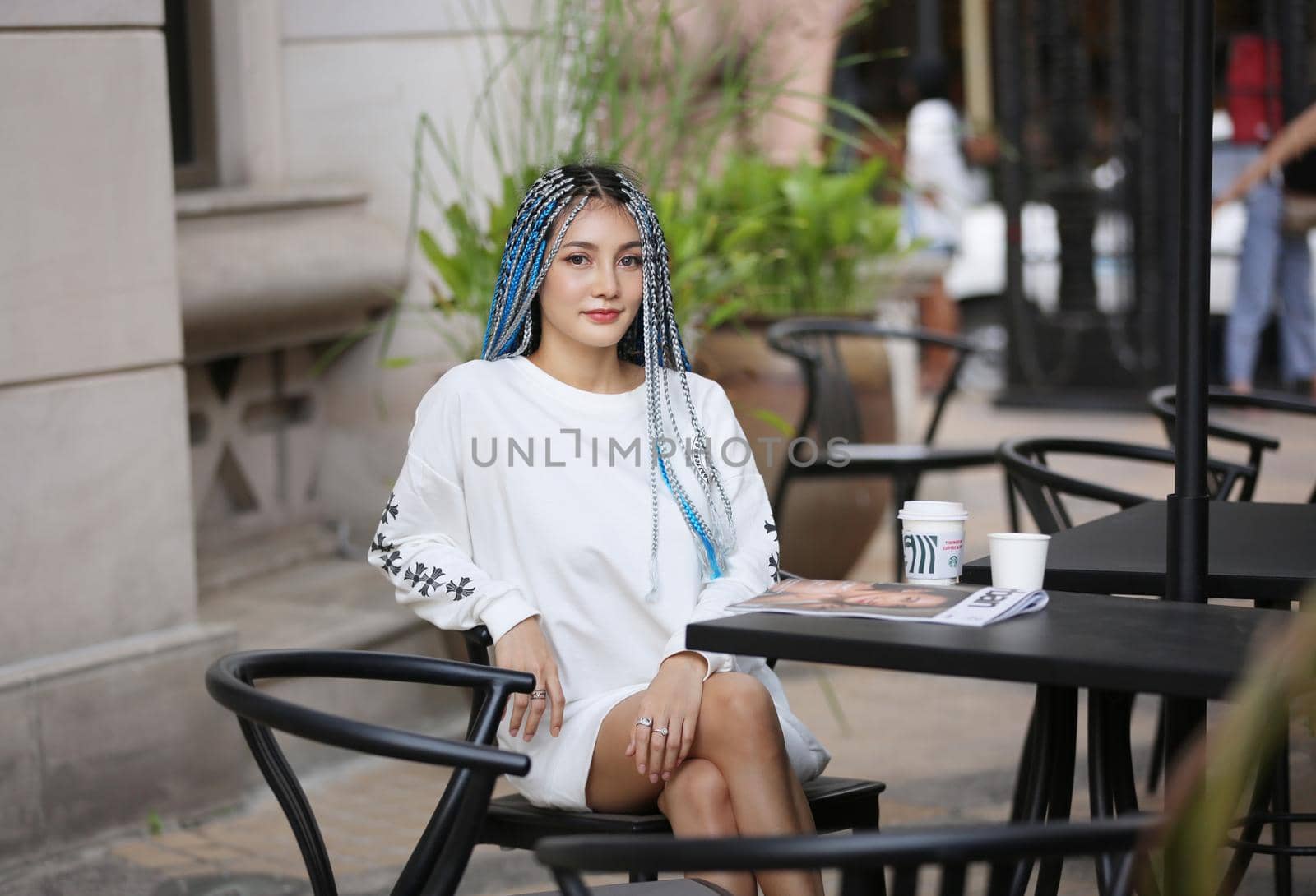 Happy stylish young hipster woman with long blue hair pink jacket, hat on the street in urban city. by chuanchai